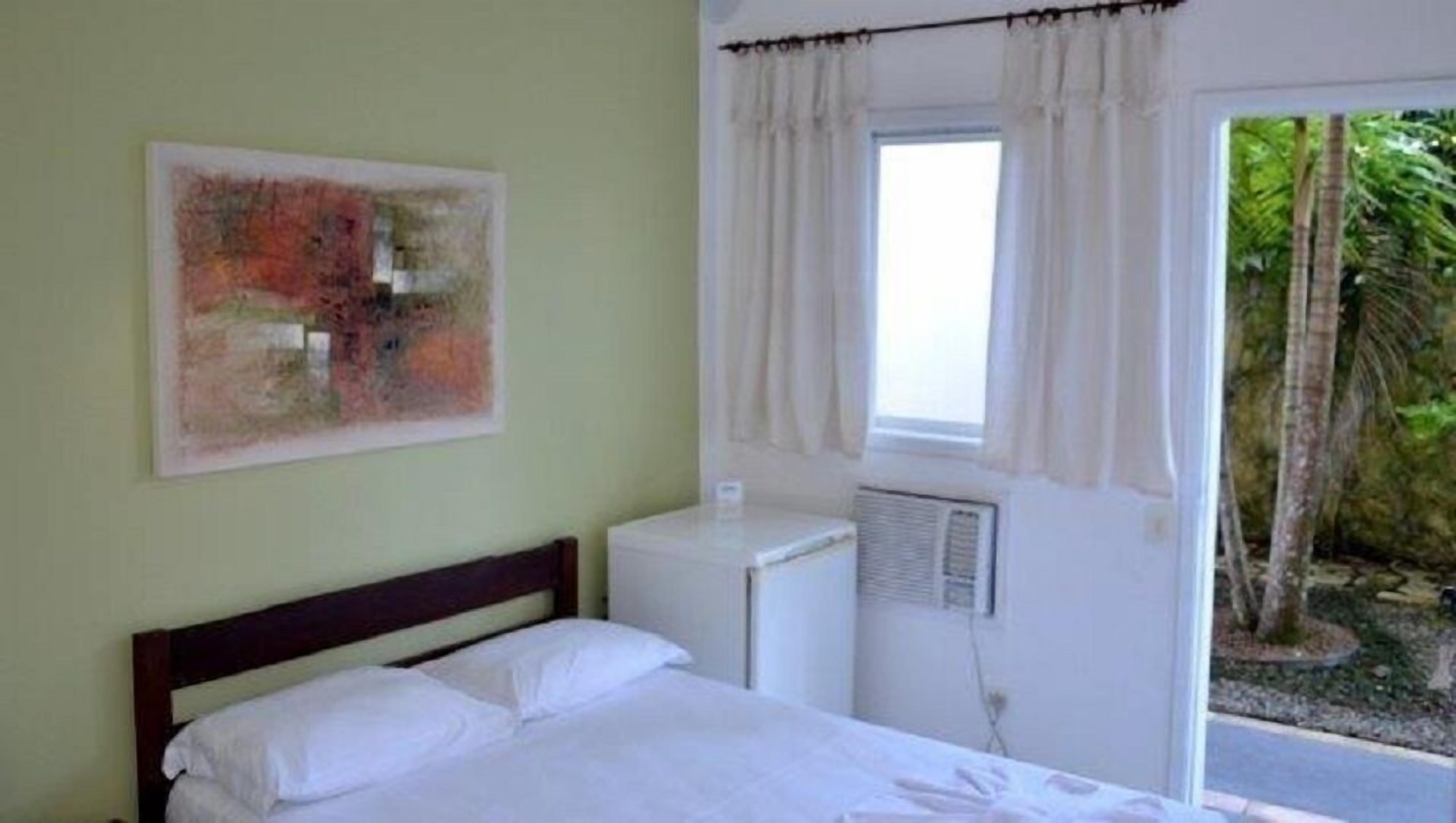 Une chambre à coucher avec un lit, une fenêtre avec des rideaux, un radiateur et un tableau accroché au mur.
