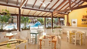 A restaurant with outdoor seating, a pool, and a bar area. - Pousada Camburioca (São Sebastião)