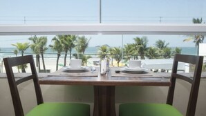 Une table à manger avec deux chaises, une vue sur la plage et des palmiers.