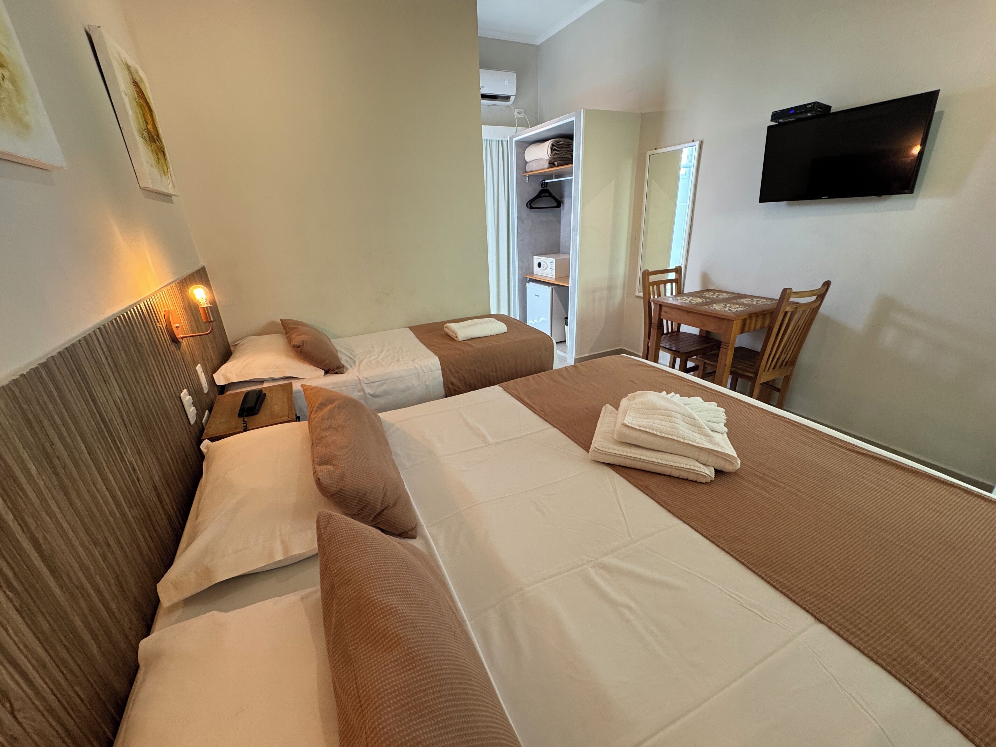 A hotel room with two beds, a desk, and a TV.