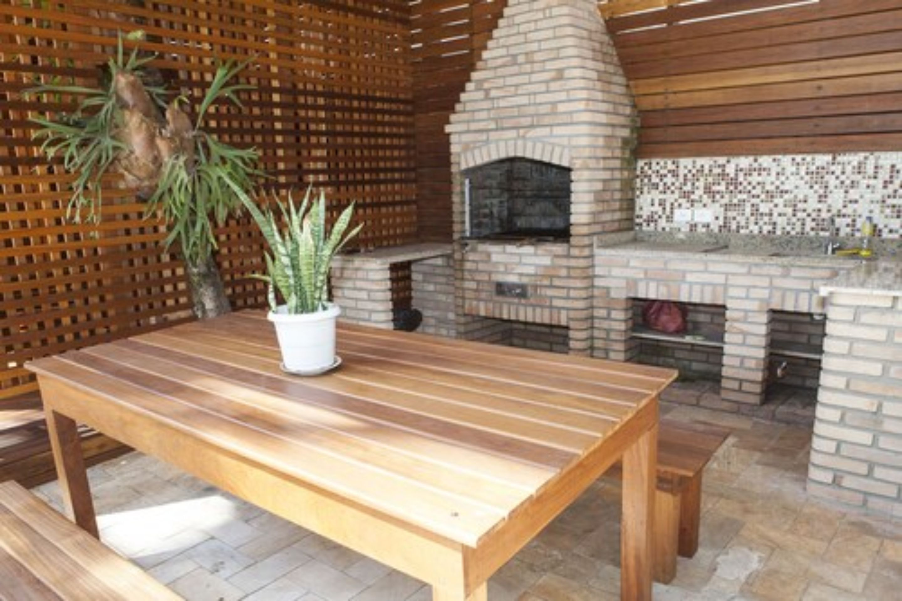 Forno de tijolos ao ar livre com mesa e bancos de madeira.