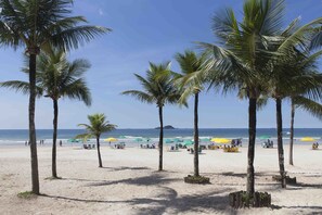 Une plage bordée de palmiers et parsemée de parasols.