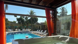 Un espace piscine comprenant un jacuzzi, des chaises longues et des parasols.