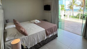Une chambre d’hôtel avec un lit, une lampe de chevet, un téléphone, un téléviseur fixé au mur et une vue sur l’extérieur par une grande fenêtre.