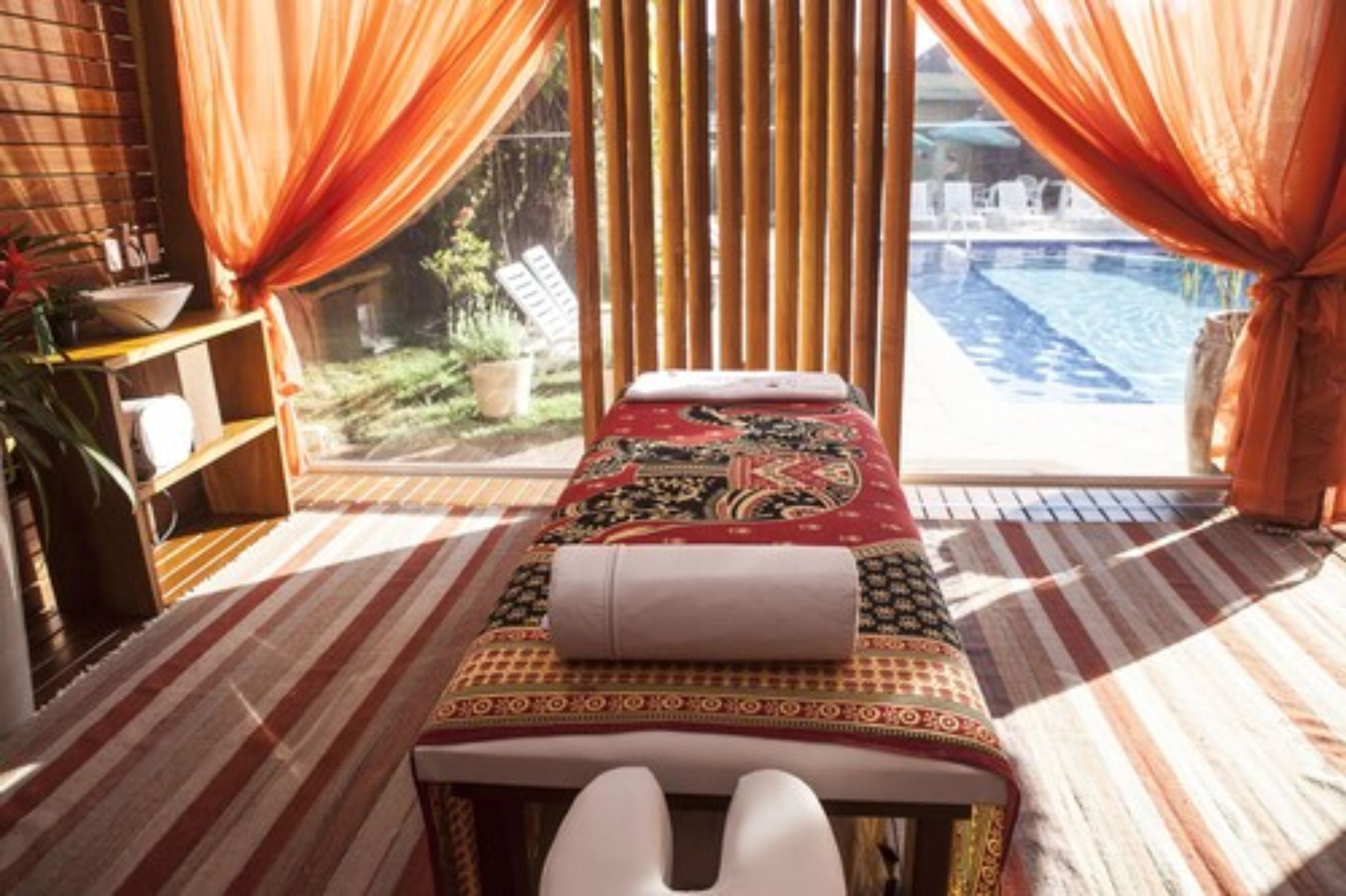 A massage room with a view of a pool and garden.