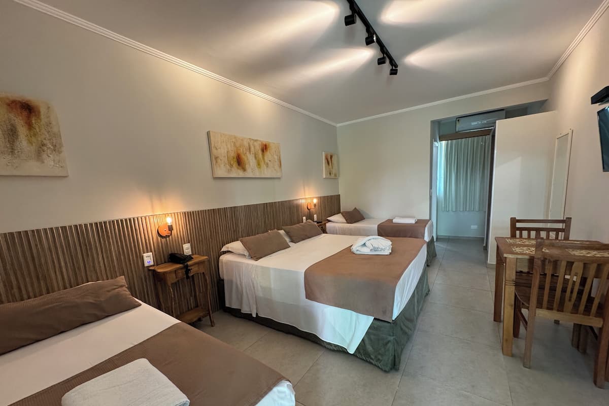 Une chambre d’hôtel avec deux lits, une tête de lit en bois, une petite table avec une chaise et des œuvres d’art accrochées aux murs.