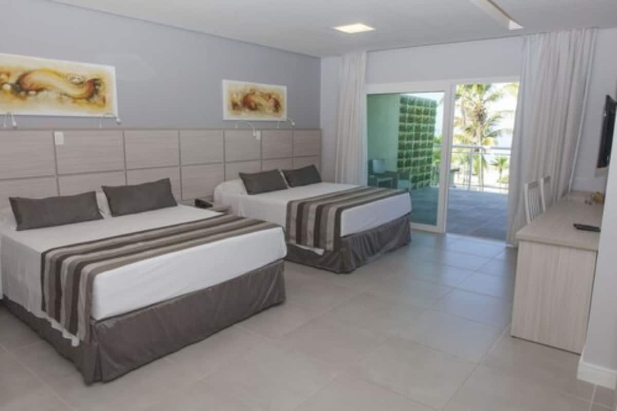 Une chambre d’hôtel avec deux lits, un bureau et une vue sur l’extérieur.