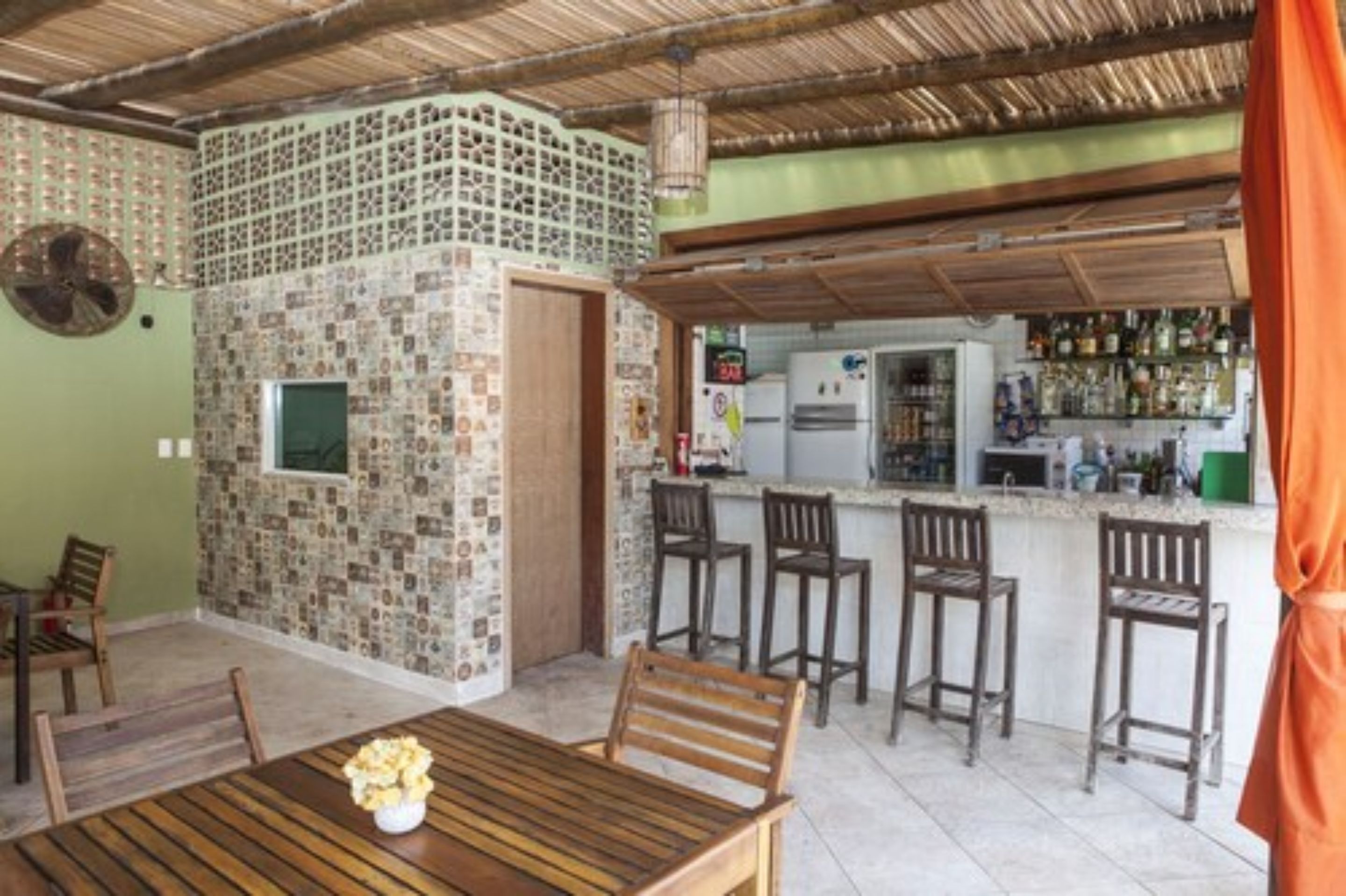 A dining area with a wooden table and chairs, a kitchen with a bar, and a patterned wall.