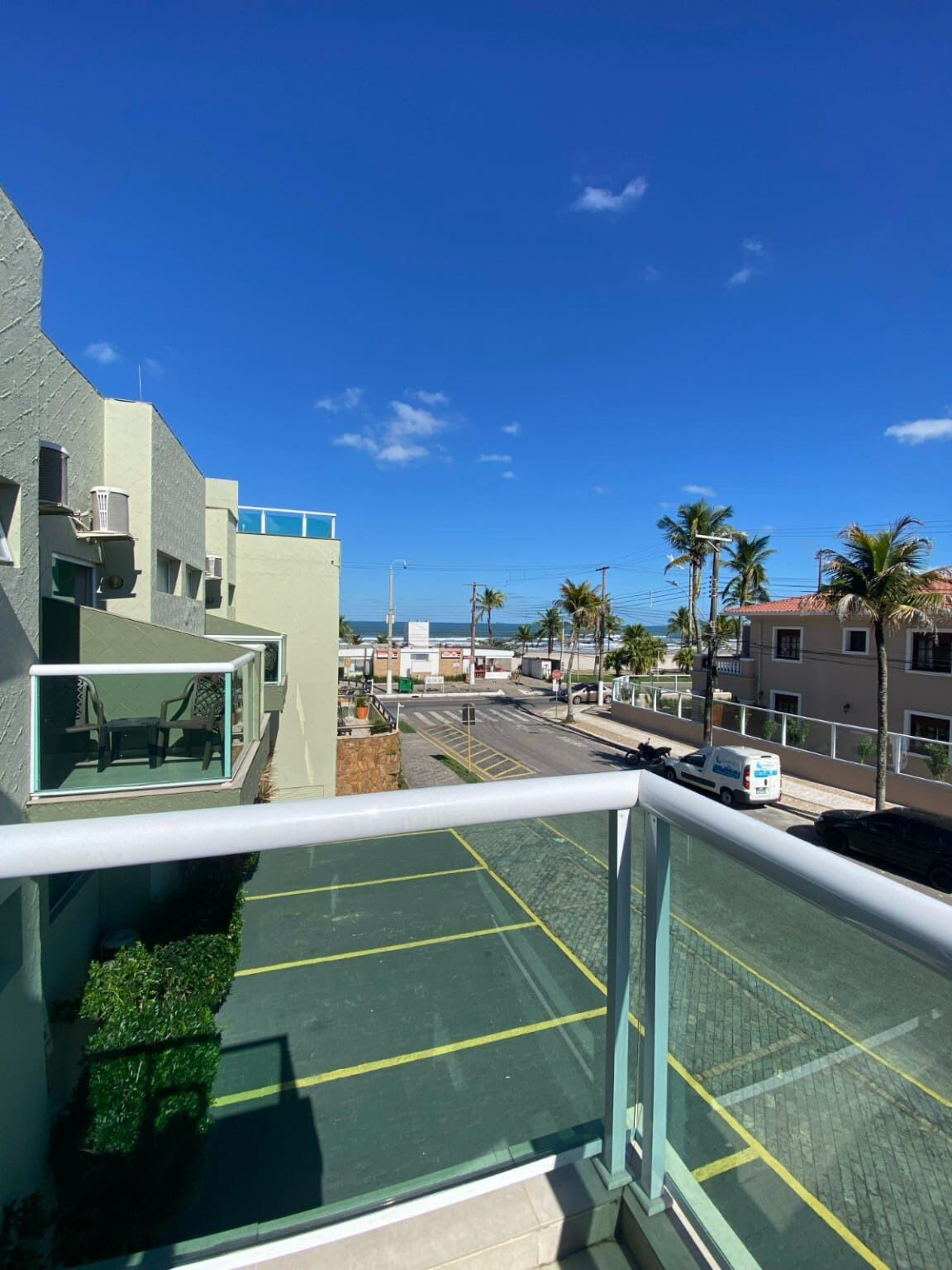 Un balcón con vistas a un estacionamiento, edificios y palmeras.