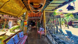 A covered outdoor area with wooden benches, a pathway, and a small pond with fish. - Pousada Papaya (Ubatuba)