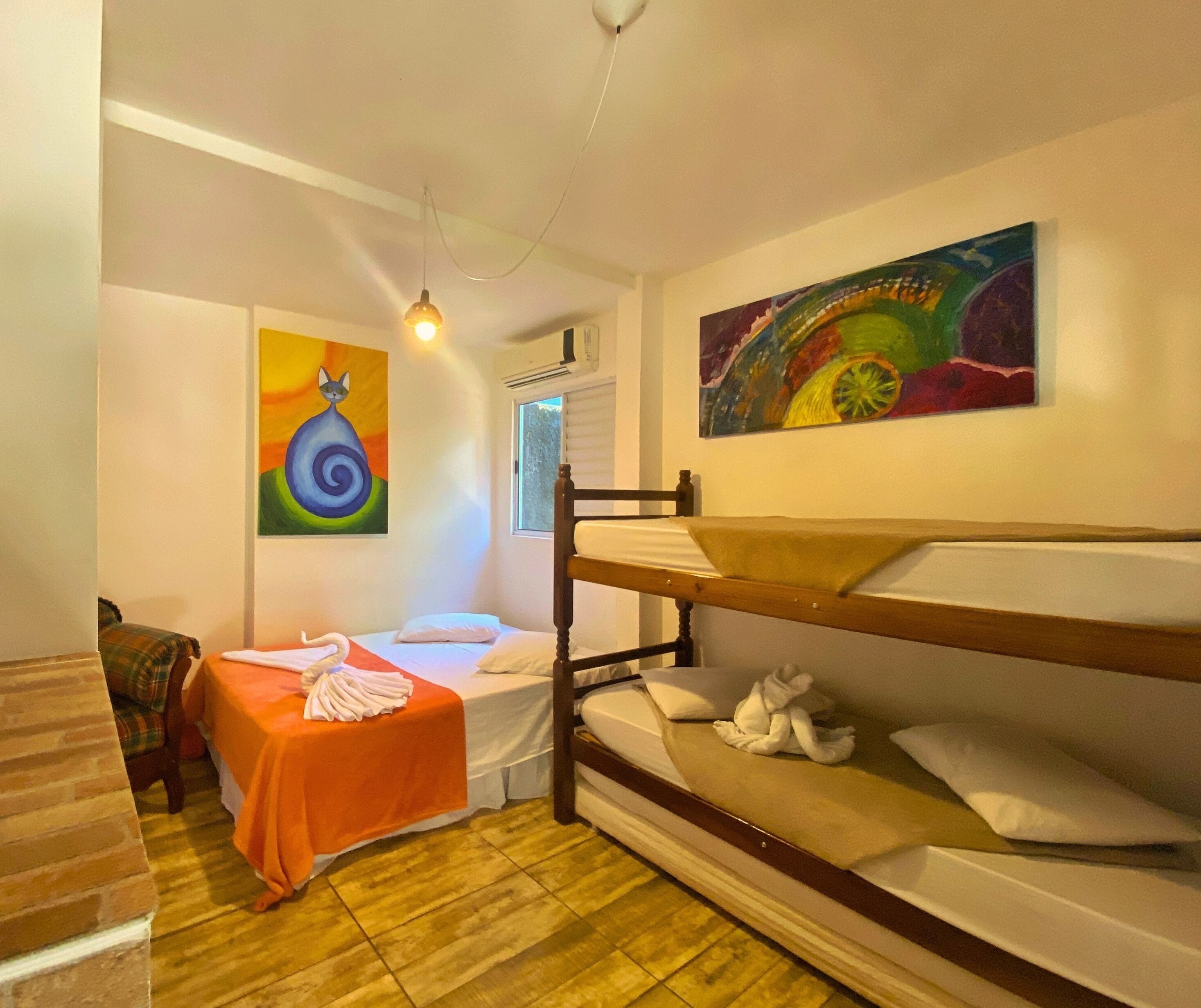 Una habitación con literas, una mesita con una toalla y dos cuadros en la pared.