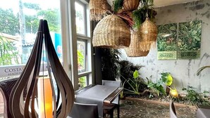 Un espace repas doté d’un sol en pierre, de luminaires suspendus en osier et offrant une vue sur la plage de Costa.