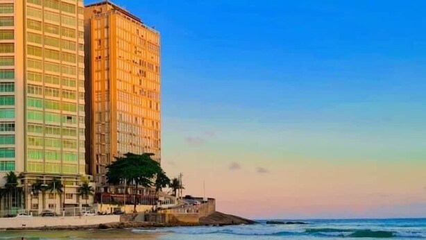 Un hôtel situé sur la côte, avec vue sur la plage, un grand bâtiment et une mer calme.