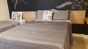 Hotellihuone, jossa on sänky, kaksi yöpöytää ja sängynpääty, jossa on koristeellinen seinätaideteos.