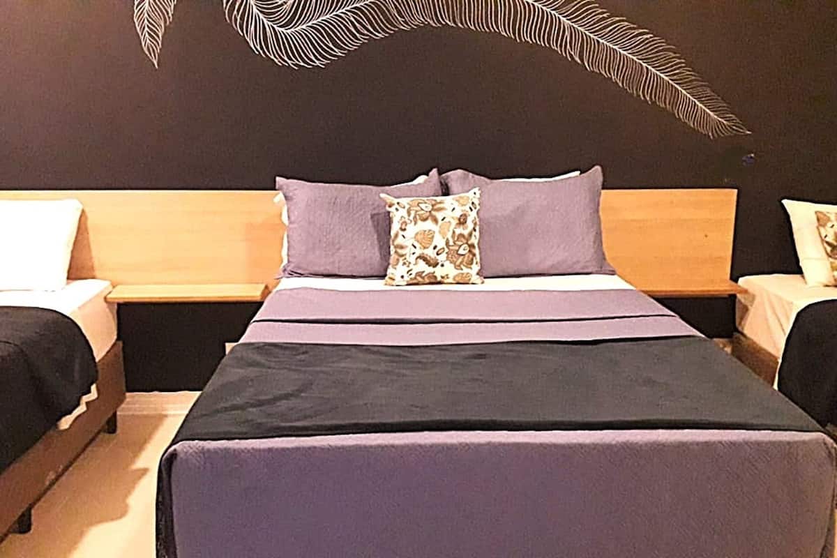 A hotel room with a large bed, two bedside tables, and a decorative wall design.