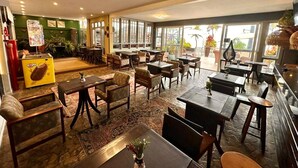 Un restaurant spacieux, doté de nombreuses tables et chaises, d’un espace buffet et de grandes fenêtres offrant une vue sur l’extérieur.