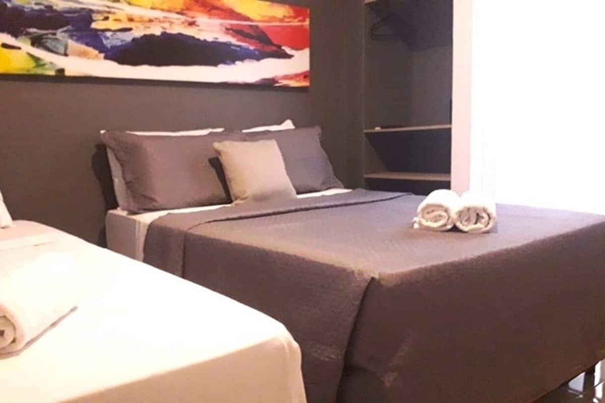 A hotel room with a bed, pillows, a blanket, and a towel.