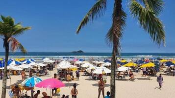 Perto da praia, areia branca, espreguiçadeiras, guarda-sóis