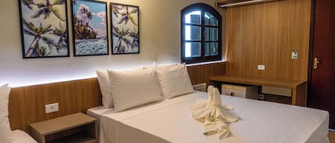 Habitación de hotel con una cama grande, un armario de madera, un escritorio pequeño y una ventana con vista a palmeras.