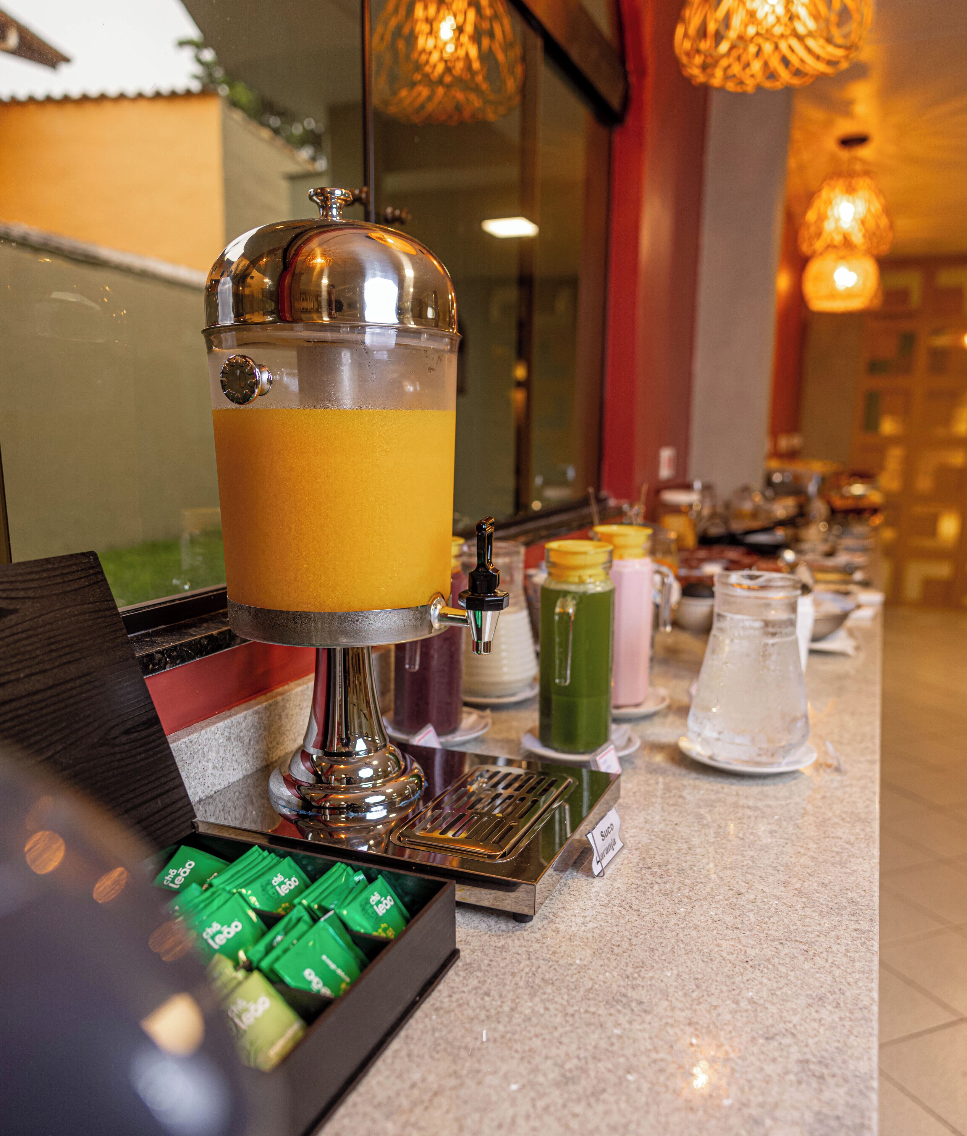 A beverage station with a large dispenser, a coffee machine, and various drink containers.