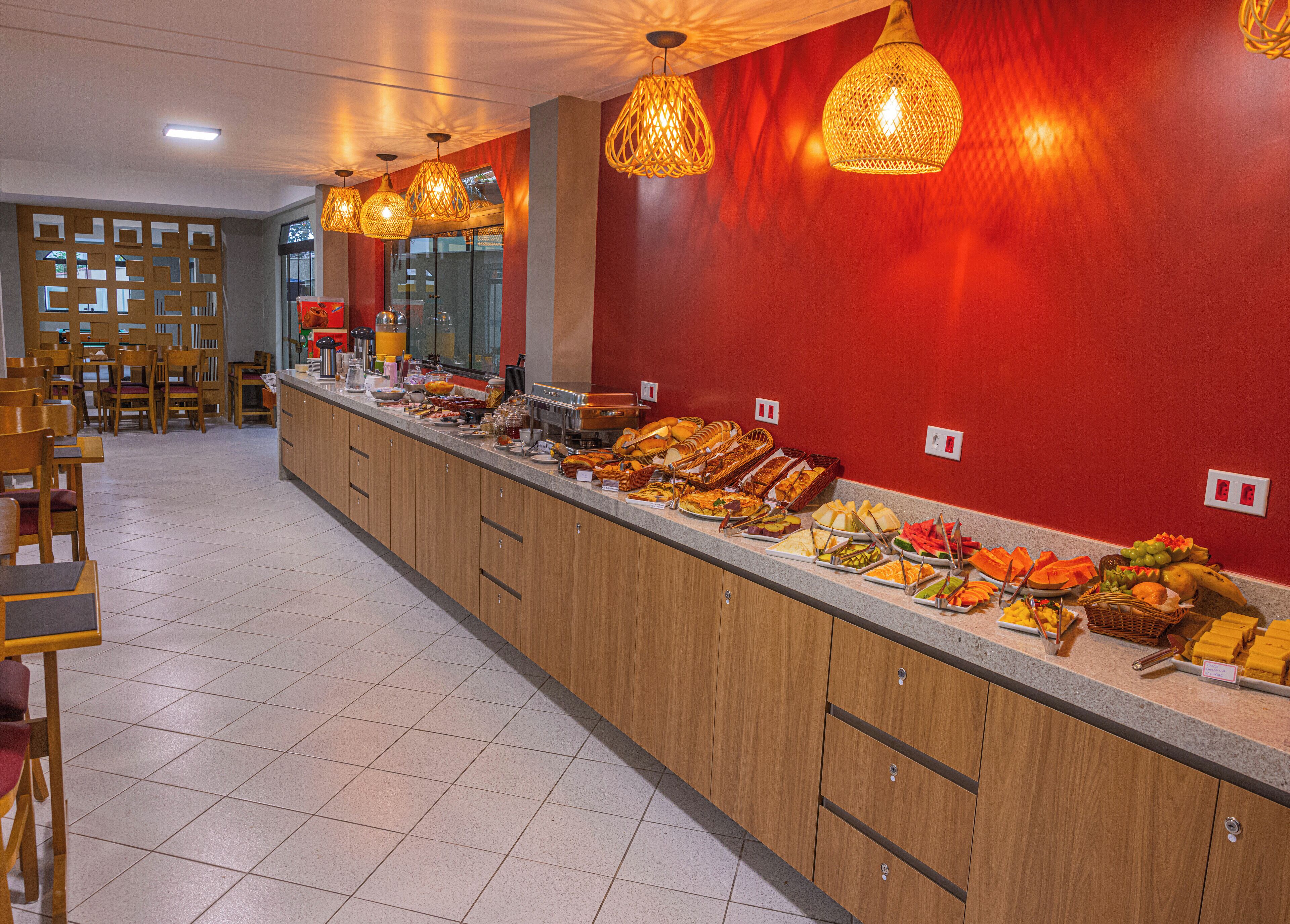 A buffet area with a variety of food items, wooden cabinets, and hanging wicker lamps.