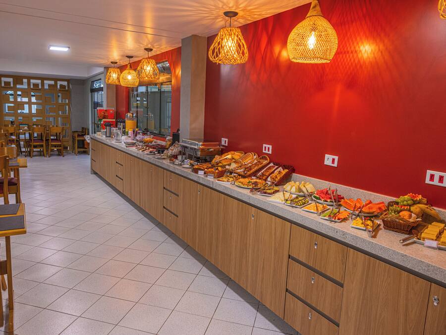 A buffet area with a variety of food items, wooden cabinets, and hanging wicker lamps.