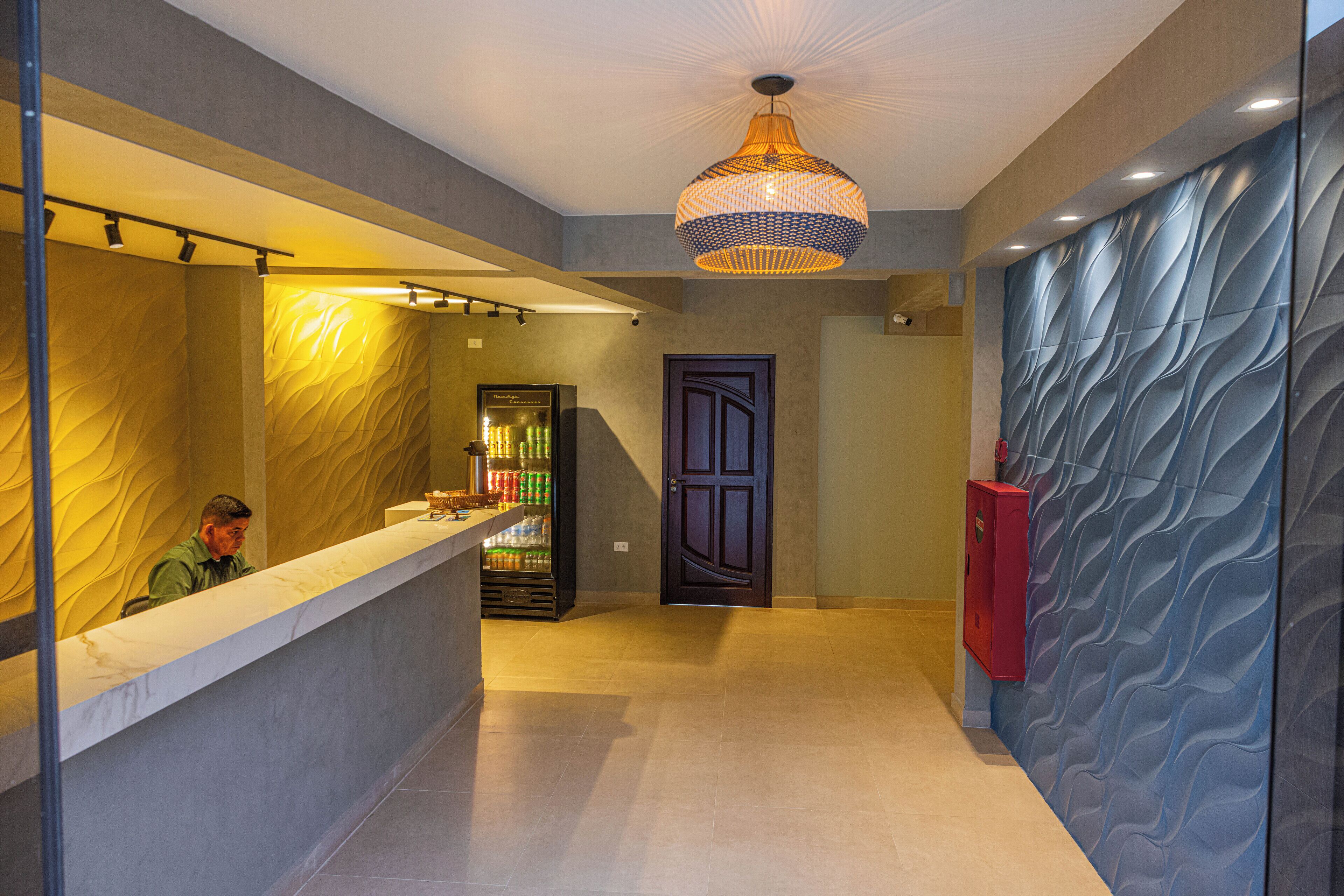 A reception area with a counter, a man seated, a door, and a patterned wall.