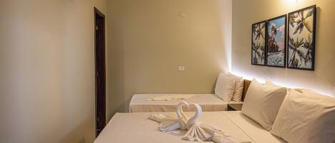 A hotel room with two beds, a wall-mounted TV, and a painting of palm trees.
