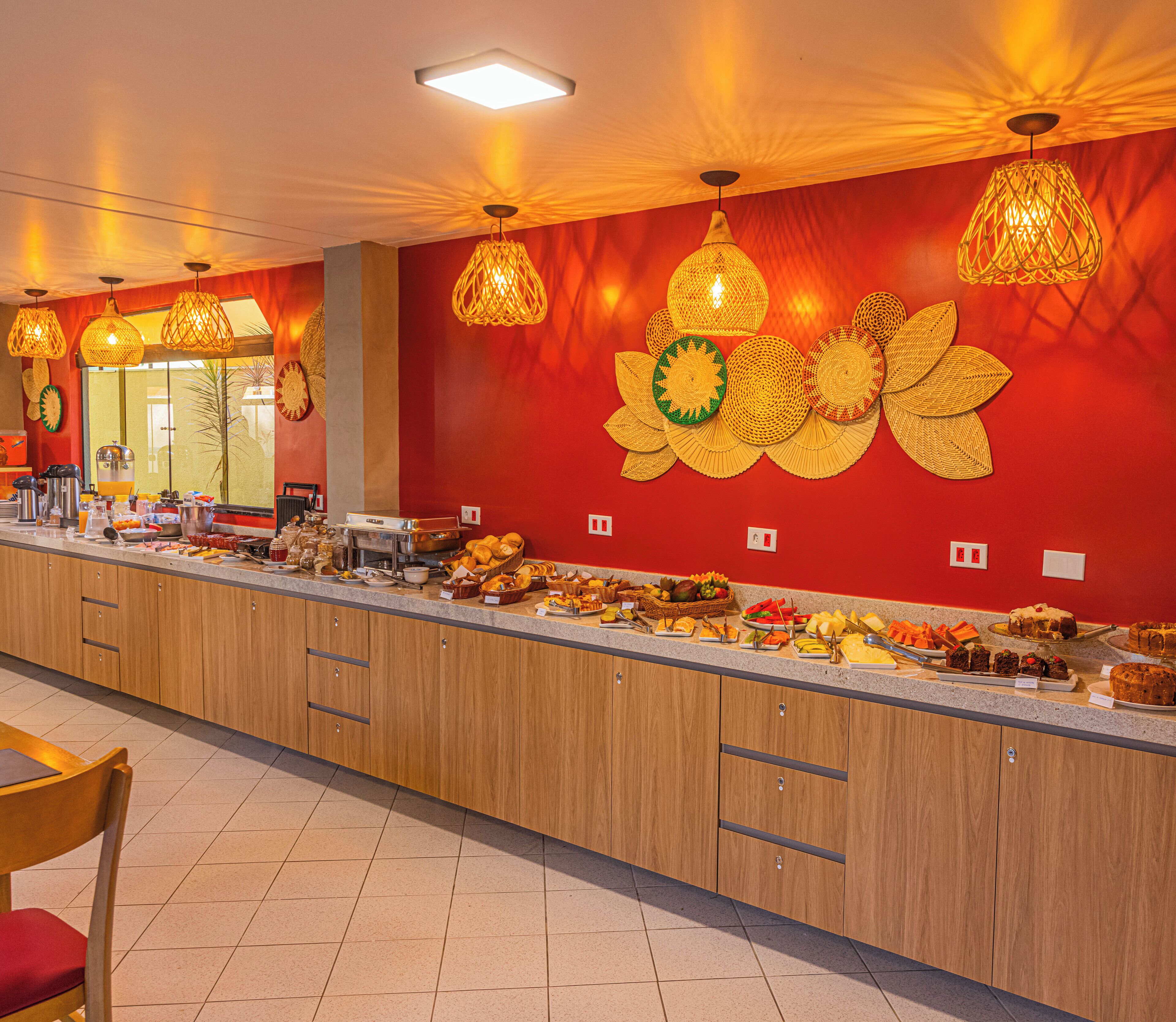 A buffet area with a variety of food items and a decorative wall with woven light fixtures.