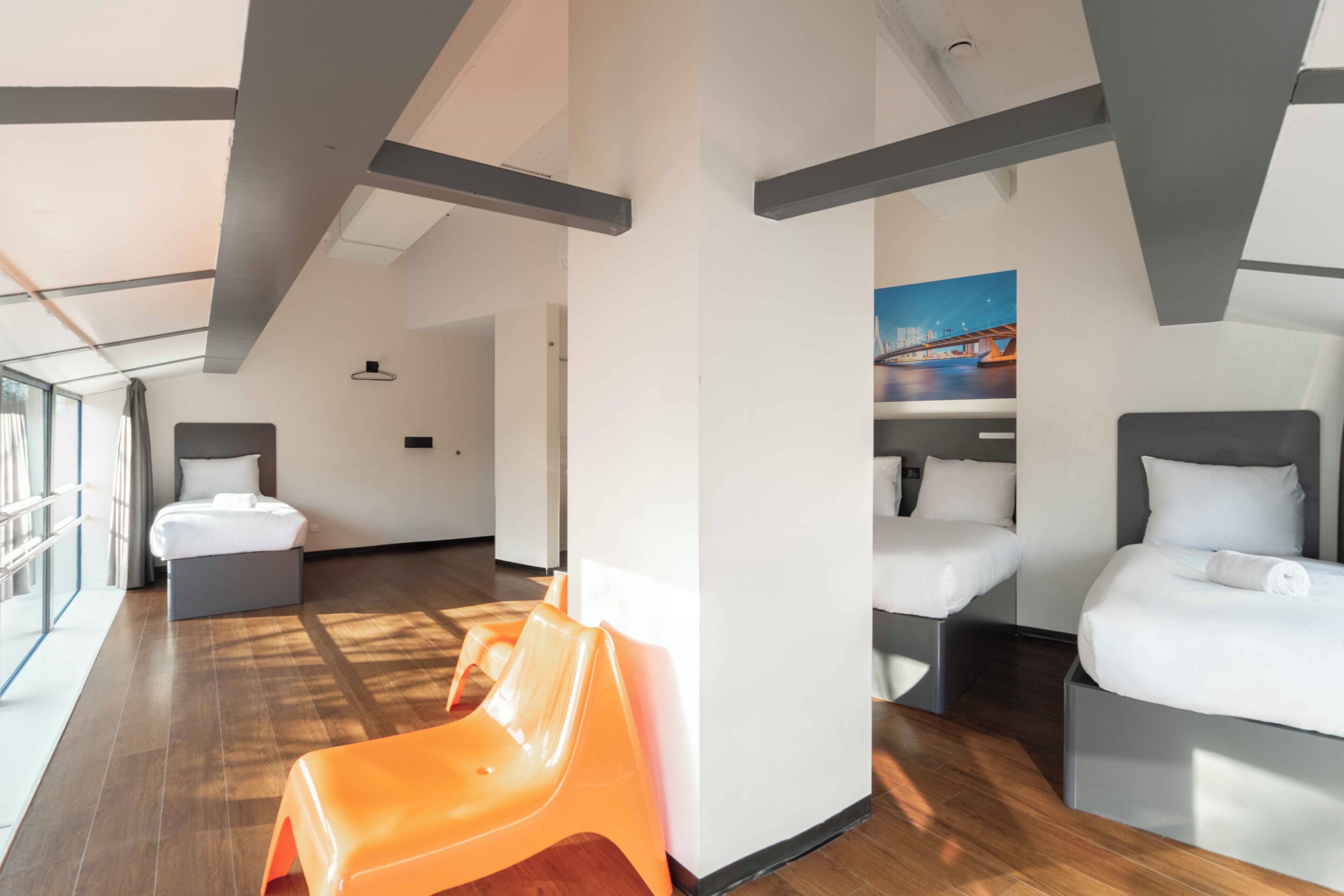 A hotel room with two beds, a window, and a painting on the wall.