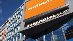 A building with a prominent orange sign reading 'easyHotel.com' and a smaller sign below it.