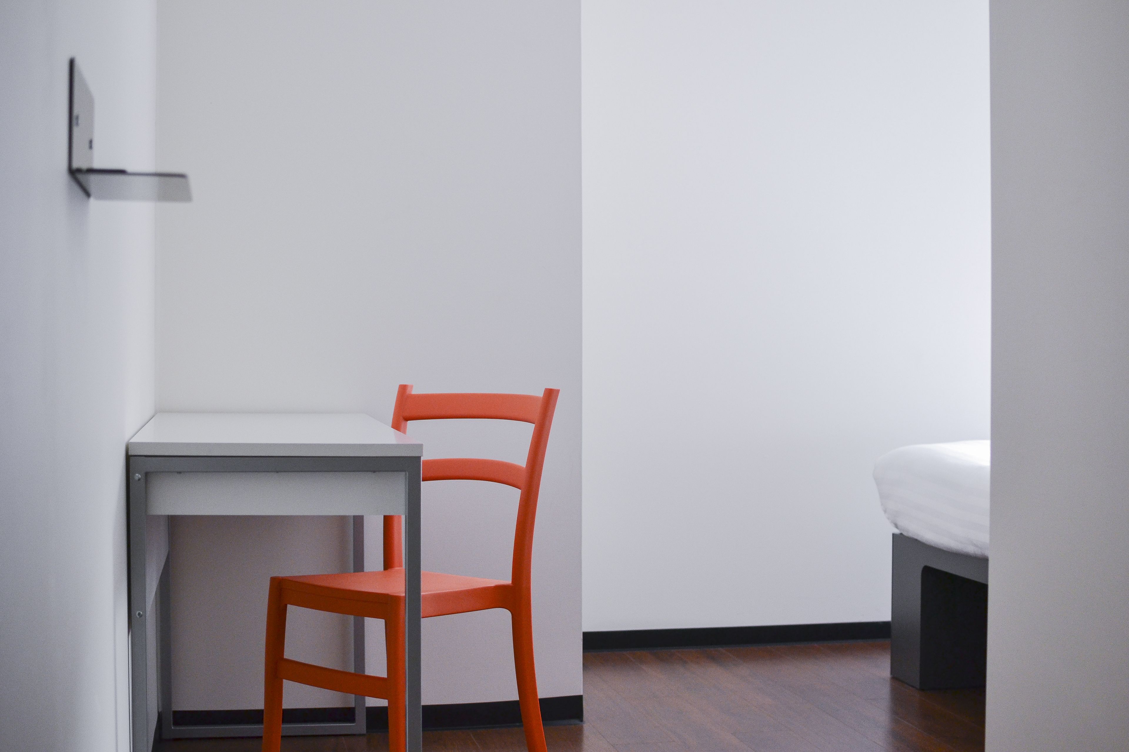 Una habitación pequeña y sencilla con escritorio, silla y cama.