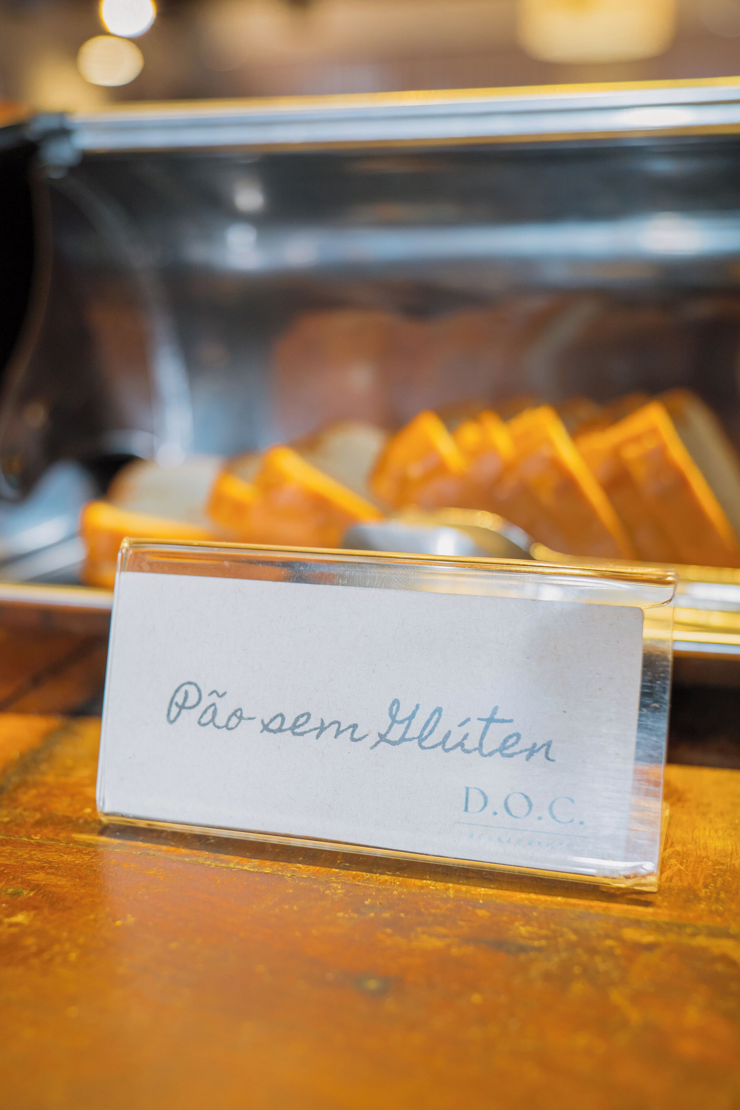 A glass display case with a sign reading "Pão sem Glúten D.O.C."