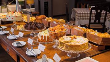 Ein Buffet mit verschiedenen Desserts und Backwaren, darunter Kuchen, Torten und Brot.