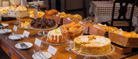 A buffet with various desserts and pastries, including cakes, pies, and bread.
