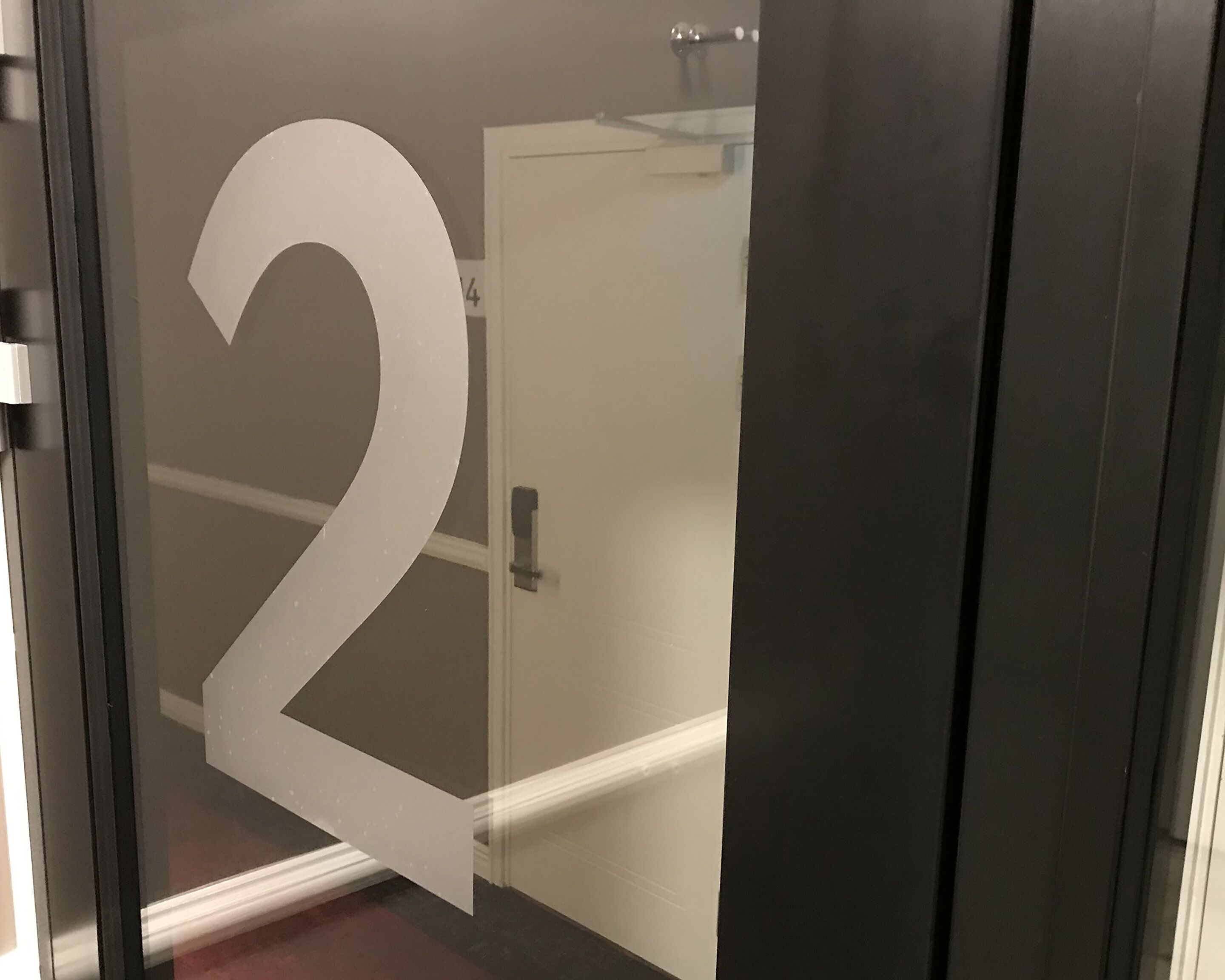 Puerta de vidrio con el número 2 grande, indicando el número de habitación.