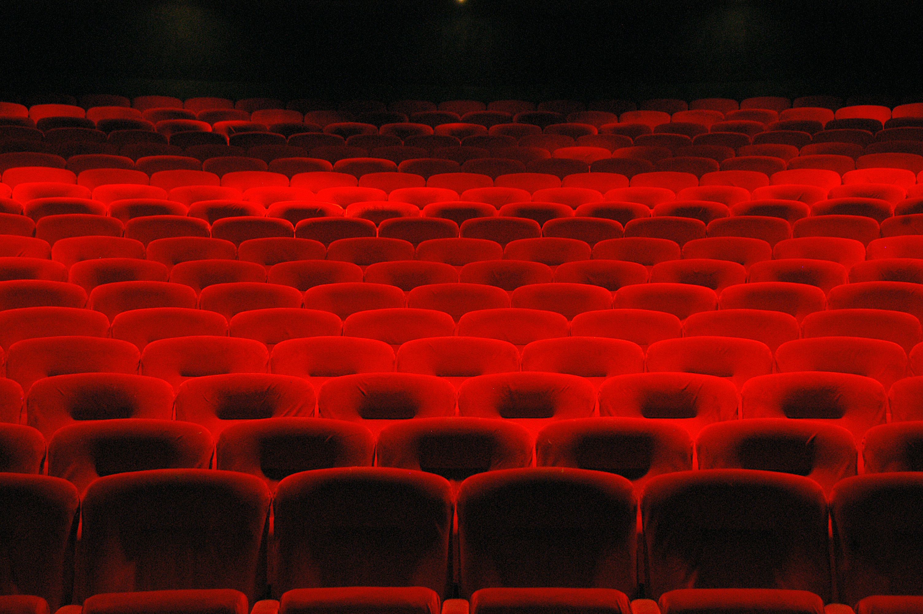 Un teatro con hileras de asientos rojos.