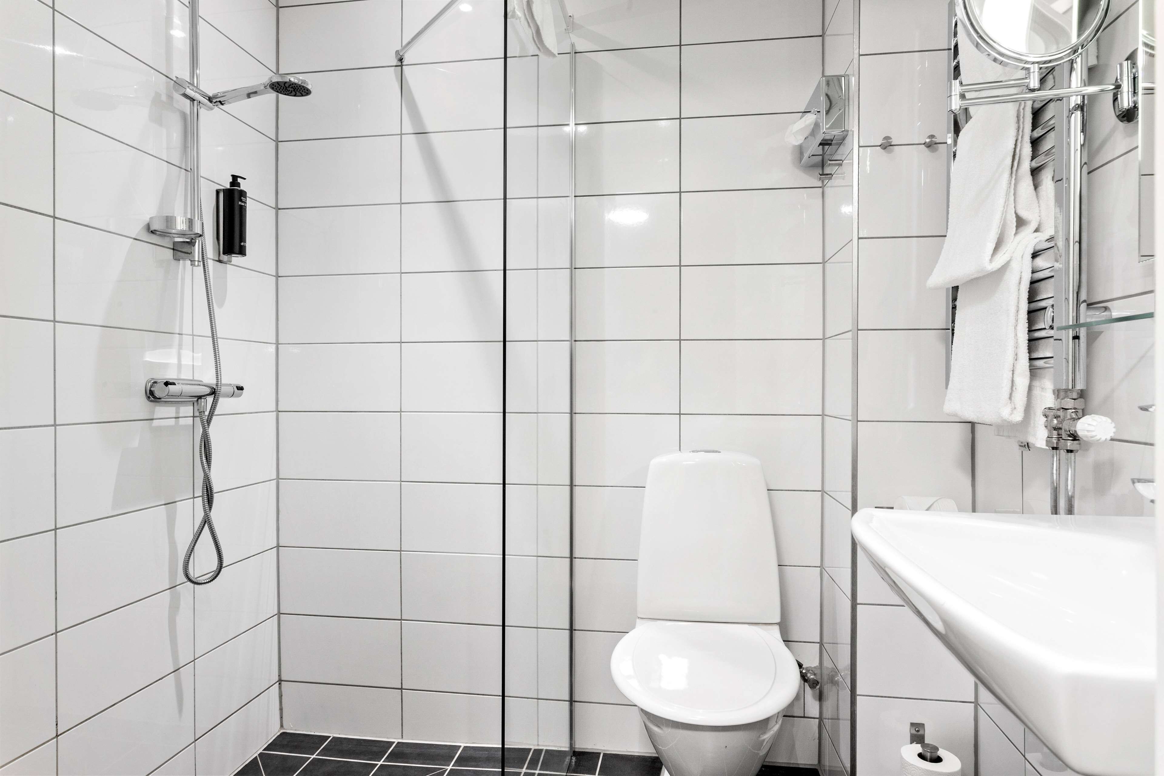 A modern bathroom with a shower, toilet, and sink.