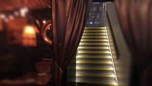 A staircase with illuminated steps leading upwards, flanked by curtains and a circular window. - Best Western Hotel Savoy (Karlstad)