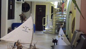 A model ship on a table, a staircase, and a sofa in a room. - Pousada Porto Belo (Ipojuca)