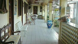 A corridor with a bench, a table, and a large vase. - Pousada Porto Belo (Ipojuca)