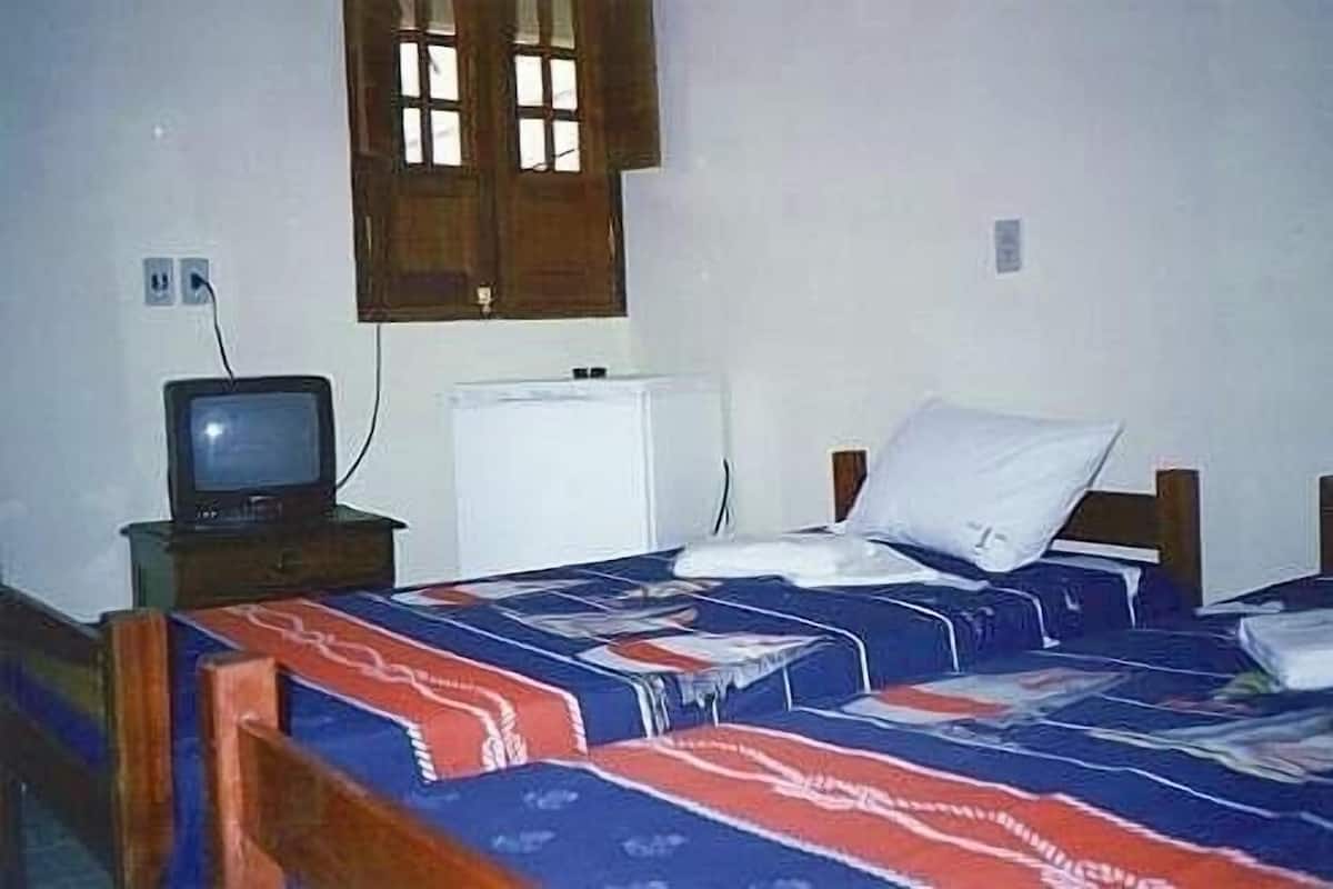 Un dormitorio con dos camas, un televisor y un pequeño electrodoméstico blanco.