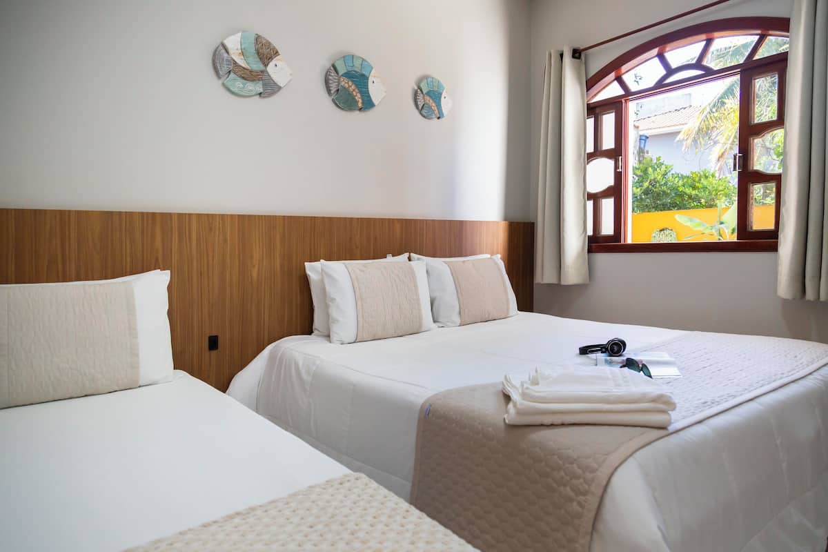 A hotel room with two beds, a wooden headboard, and a window with curtains.