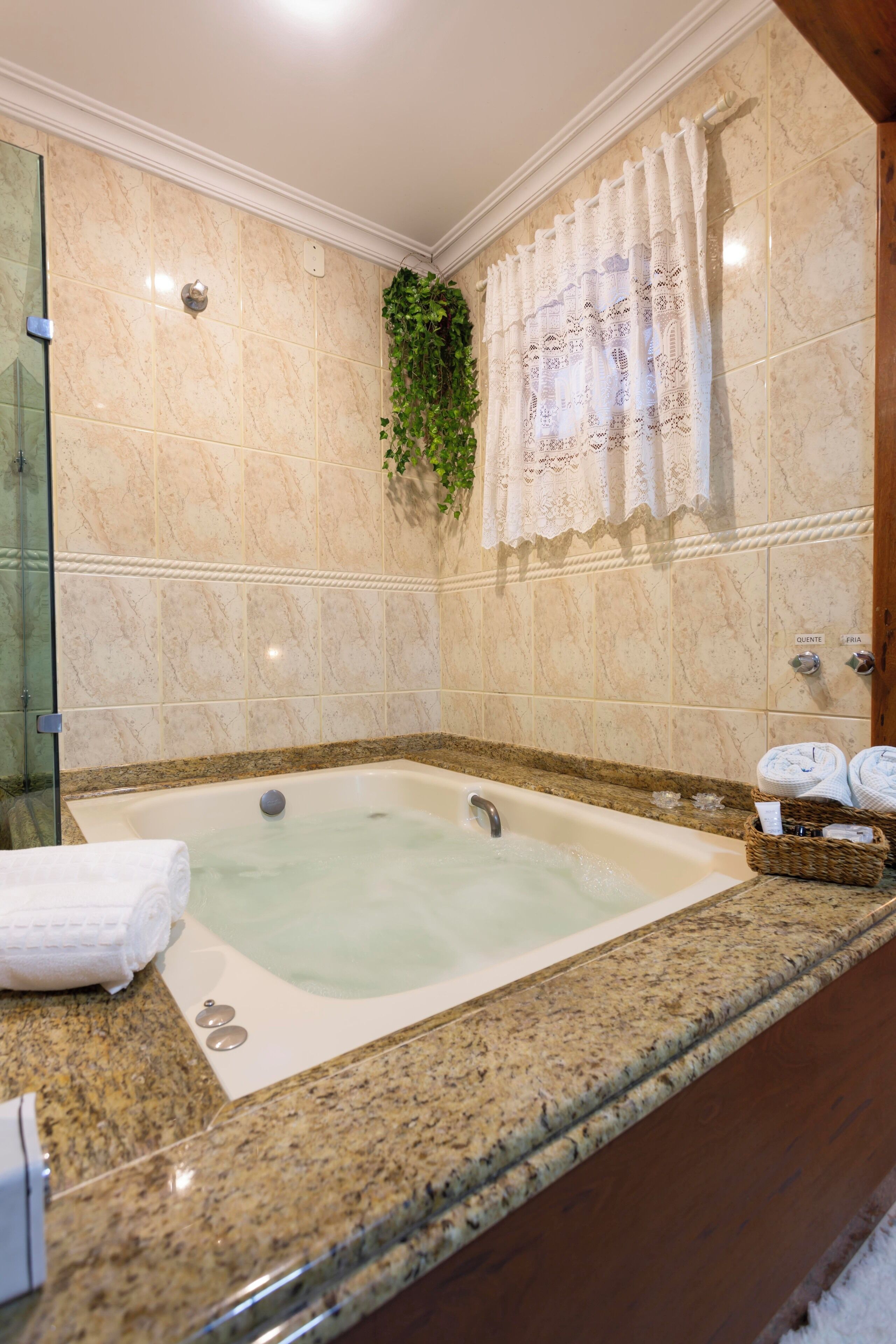 Un baño con una bañera grande, azulejos de mármol, cabina de ducha de cristal y un perchero para toallas.