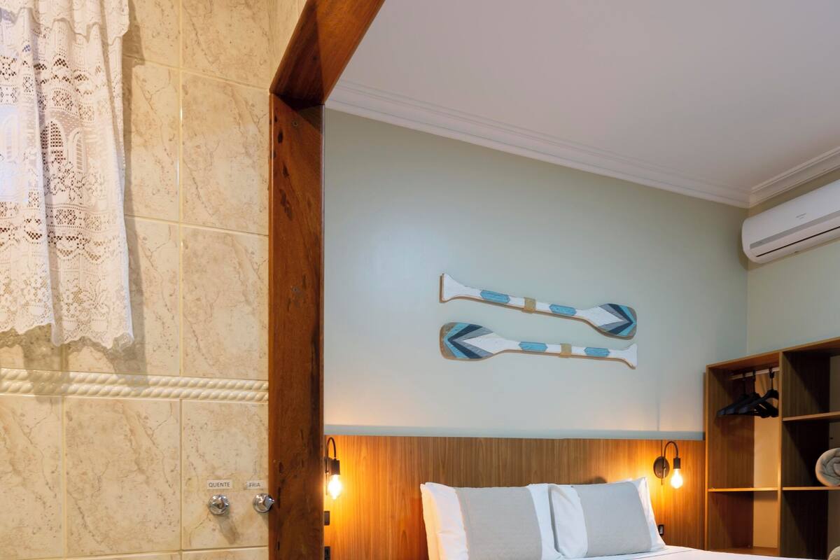 A hotel room with a large bathtub, a bed with white linens, a wooden headboard, and a wall-mounted towel rack.