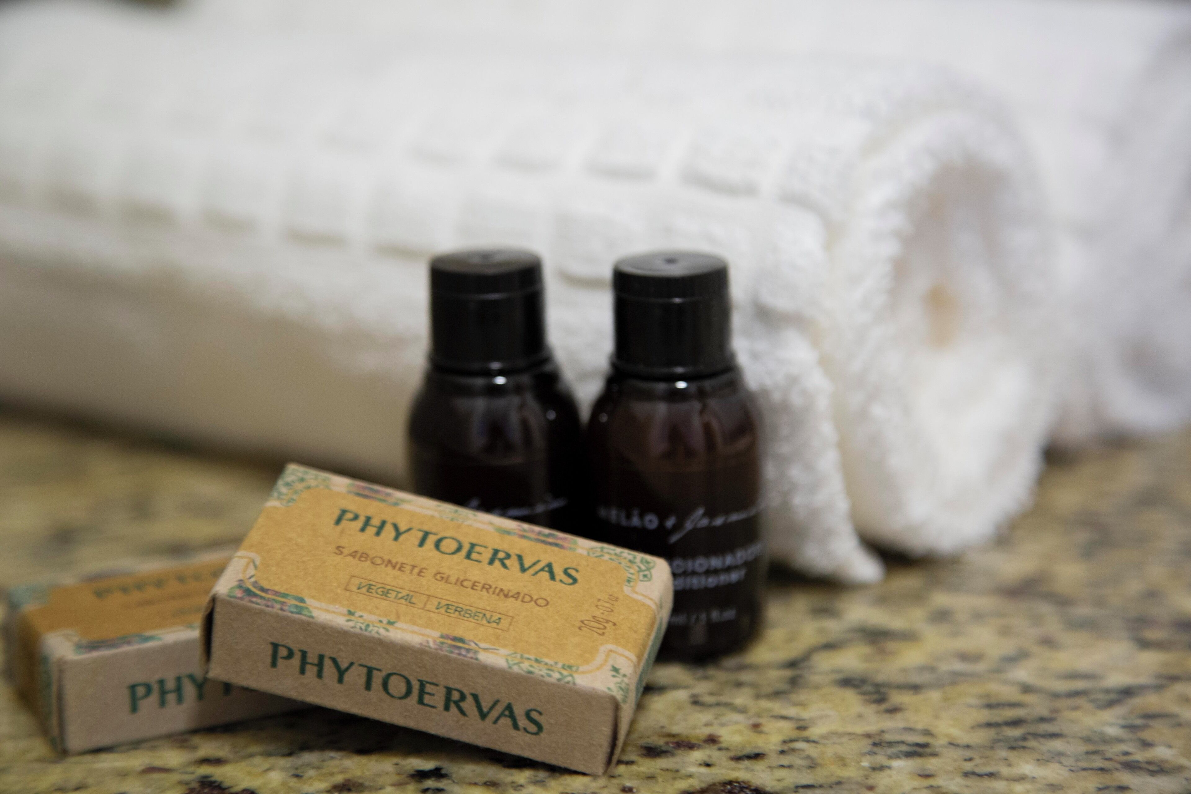 A bathroom with a white towel, two small bottles, and a box labeled 'PHYTOERVAS'.
