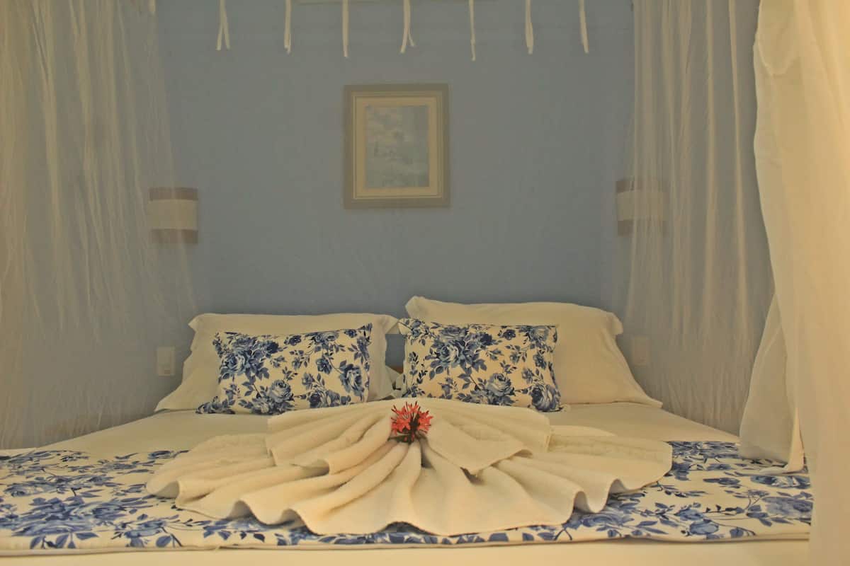A bed with a floral bedspread, two pillows with a blue floral pattern, and a white canopy.