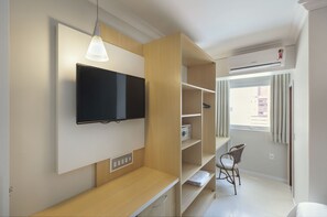 A modern room with a mounted TV, wooden shelves, a desk, and a chair.