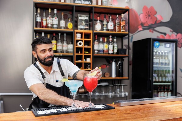 A bartender at a bar with a keyboard and a drink in front of him.
