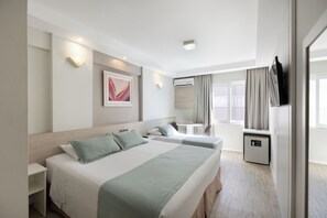 A hotel room with two beds, a desk, a chair, a small table, a wardrobe, and a window with curtains. - Hotel Miramar (Balneário Camboriú)